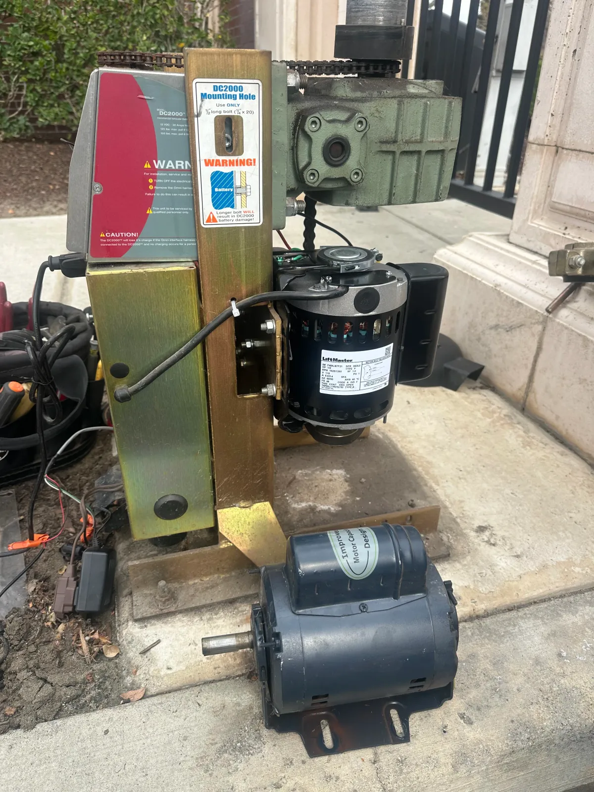 Old industrial machine with a red control panel, black motor, and detached motor on a concrete step outdoors in Bakersfield, CA